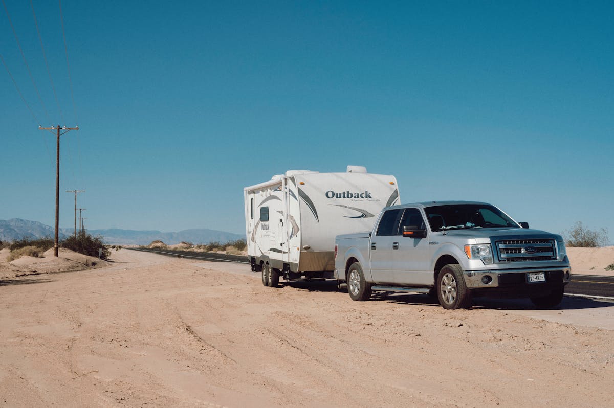A truck towing a trailer level on the road.