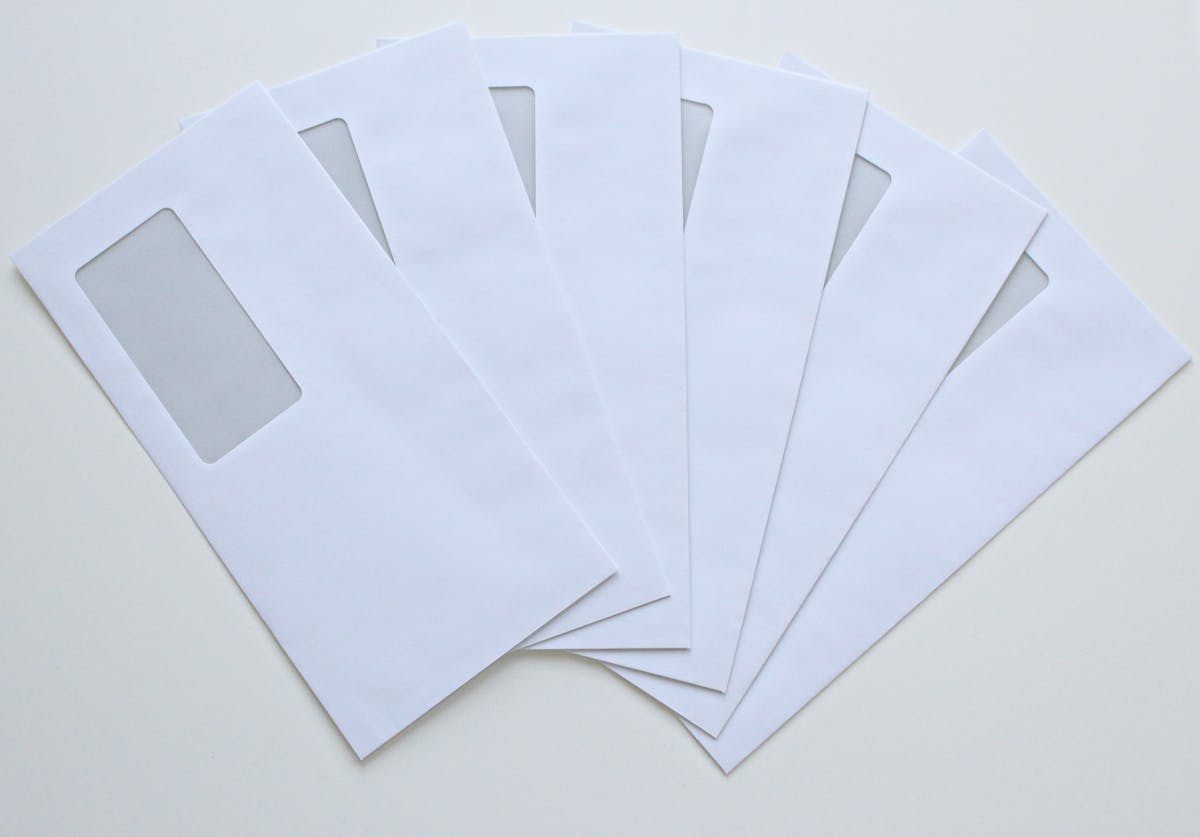 A set of white window envelopes fanned out on a flat surface.