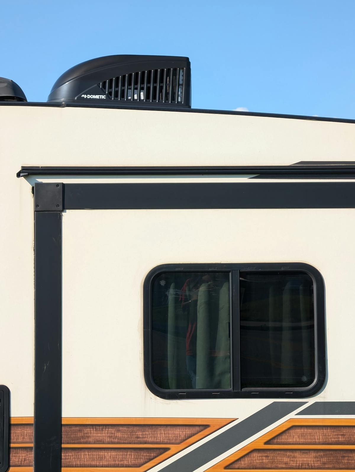A close-up of an RV exterior wall showing a roof and side joint.