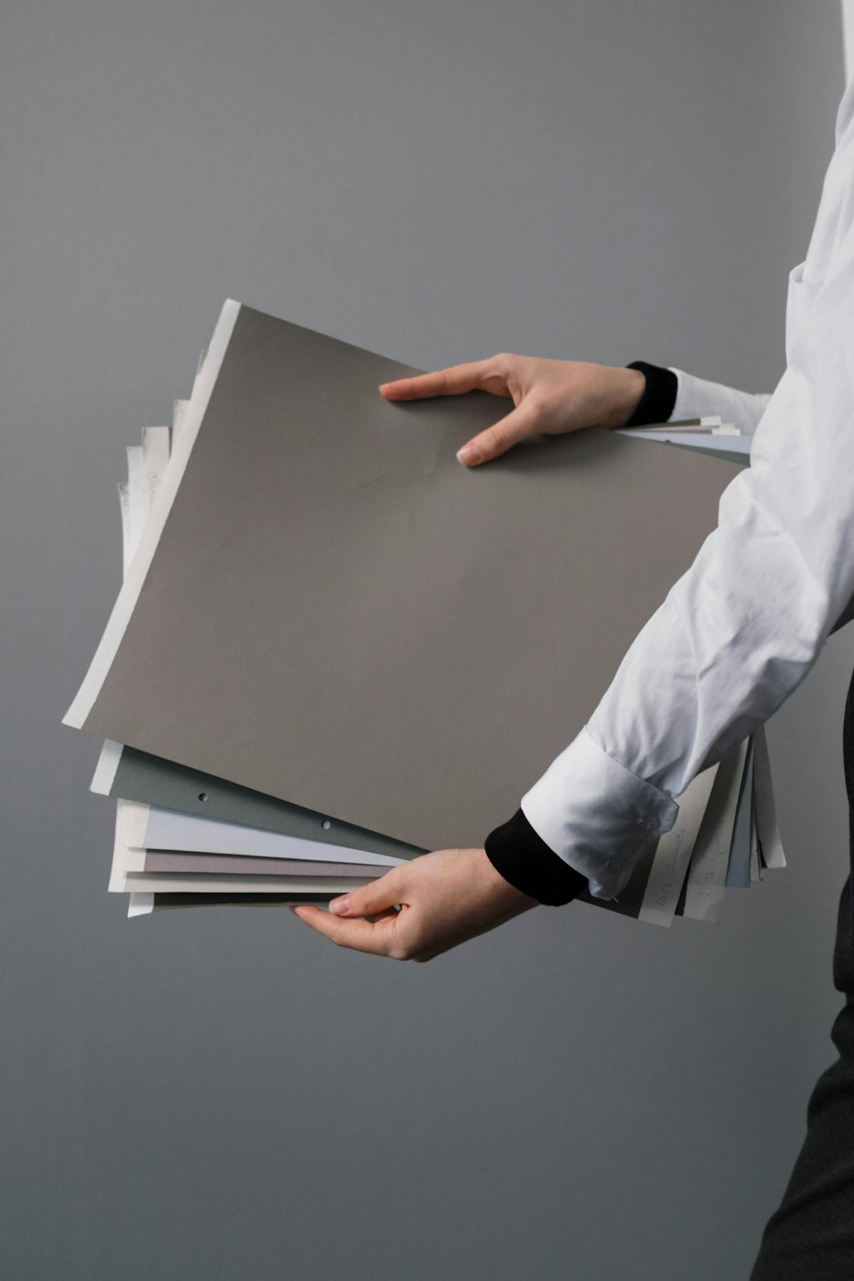Hands holding a stack of colored and white papers.