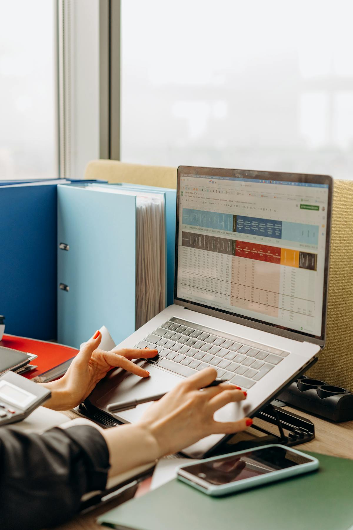 A laptop screen with analytics and folders open on a desk.